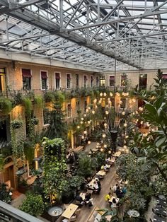 the inside of a building with lots of plants and people sitting at tables in it