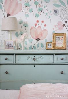 a dresser with flowers painted on the wall behind it