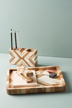 two wooden trays with pens and pencils on them