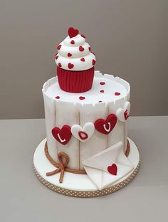 a cupcake decorated with hearts on top of a cake