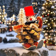 a snowman made out of pine cones sitting on top of a rock