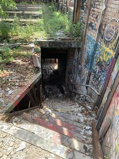 an abandoned building with graffiti on the walls and steps leading up to it's entrance