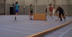 four people are playing tennis in an indoor court with boxes and rackets on the floor