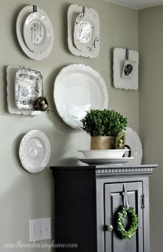 plates are arranged on the wall above a cabinet with a potted plant in it