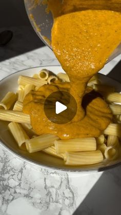 someone pouring sauce on some pasta in a bowl