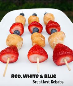 red, white and blue fruit skewers are arranged on a plate with strawberries