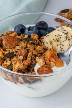 a bowl filled with granola, blueberries and yogurt on top of a table