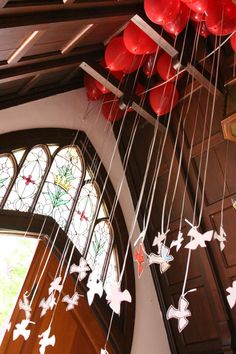 an image of some red and white balloons hanging from the ceiling in front of a church