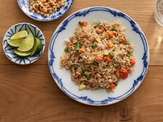 a plate with rice, peas and carrots on it next to two glasses of water