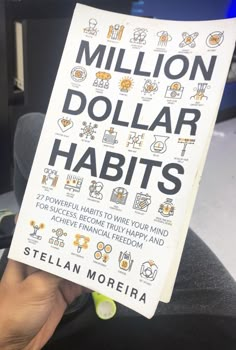 a person holding up a book about million dollar habitts