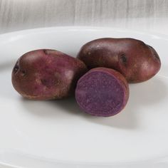 three purple potatoes on a white plate