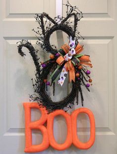 a decorated halloween door hanger with the word boo spelled out in front of it