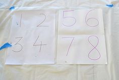 two pieces of paper with numbers on them sitting on a sheet of white paper next to blue tape