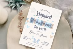 a baby shower on earth card sitting on top of a plate next to a plant