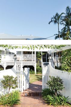 a white house with an open porch and trellis on the front door is surrounded by greenery