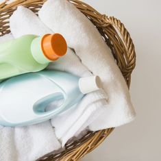 a basket filled with towels and bottles next to a bottle on top of a towel