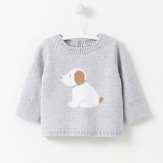 a sweater with a dog embroidered on the front and back, hanging from a hook