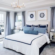 a bedroom with blue and white decor on the walls, windows, and bedding