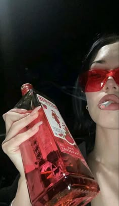 a woman wearing sunglasses and holding a bottle of alcohol