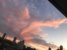 the sky is pink and blue with some clouds in front of buildings at sunset or dawn