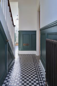 a hallway with black and white checkered flooring, green painted walls and stairs