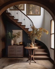 an entry way with stairs and vases on the table