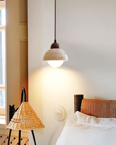 a bed room with a neatly made bed and a light hanging from the ceiling above it