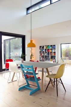 a dining room table with colorful chairs around it