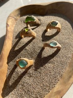 three pieces of wood sitting on top of sand with sea glass in the middle and one piece missing