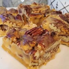 several pieces of dessert sitting on top of a white plate with pecans in the middle