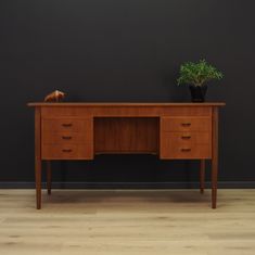 a wooden desk with two drawers and a potted plant sitting on top of it