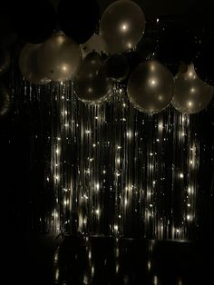 balloons and streamers hanging from the ceiling in front of a black backdrop with lights