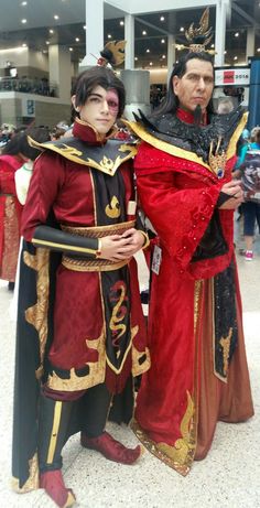 two men dressed up in costumes standing next to each other at an indoor convention center