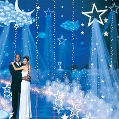 a man and woman standing in front of a stage with stars hanging from the ceiling