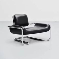 a black leather chair sitting on top of a white floor next to a metal frame