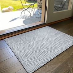 a door mat on the floor in front of a glass door with an open patio door