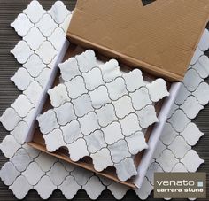 a cardboard box sitting on top of a tile floor next to a white flower pattern