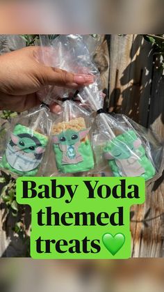 baby yoda themed treats are wrapped in plastic and placed next to a wooden fence