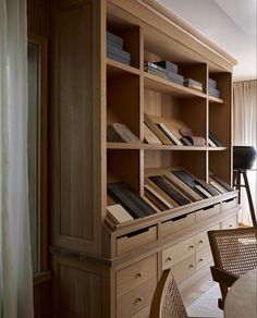 a wooden bookcase with many books on it in a living room next to a window