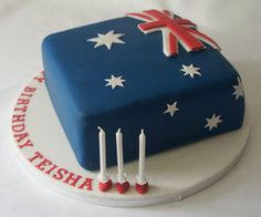 a birthday cake decorated with candles and an australian flag on the top is blue, white and red