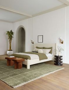 a bed sitting on top of a wooden floor next to a table and potted plant