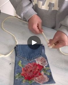 someone is making something out of old jeans with flowers on the pocket and threading them together