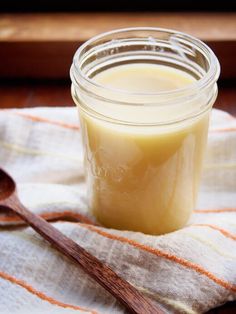 a glass jar filled with liquid sitting on top of a wooden spoon