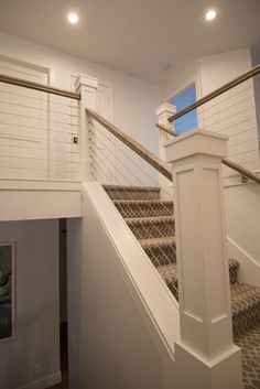 there is a stair case in the house with white walls and wood railings on both sides