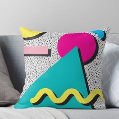 a colorful pillow sitting on top of a couch next to a gray throw pillow with an abstract design