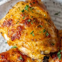 two pieces of chicken covered in cheese and parsley on top of a white plate