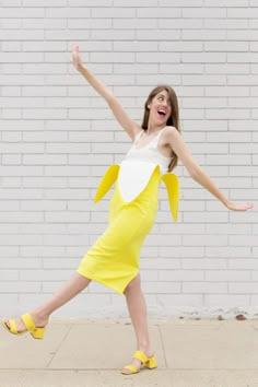 a woman in a yellow and white dress is dancing with her arms spread out to the side