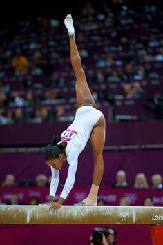 four pictures of a woman doing gymnastics on the balance beam in front of an audience