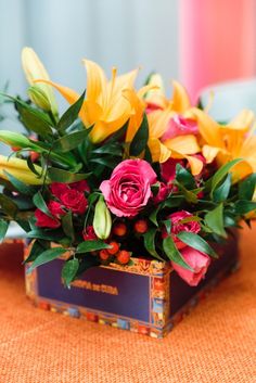 a vase filled with flowers sitting on top of a orange table cloth covered tablecloth