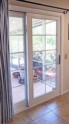 an open door leading to a patio with sliding glass doors and tile flooring in front of it